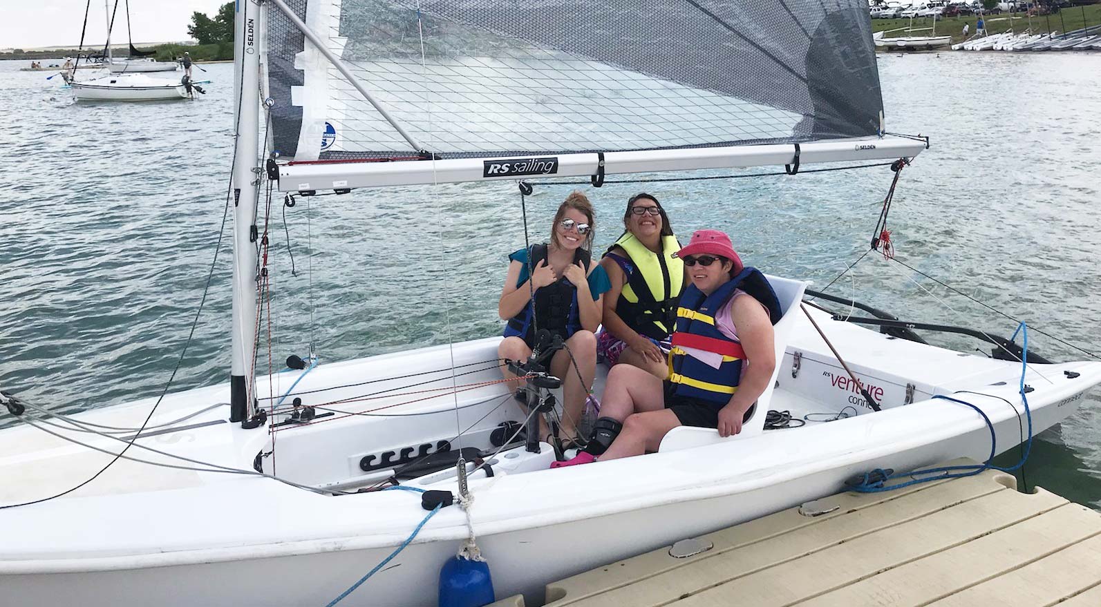 Adults with disabilities outdoors sailing on a small boat.
